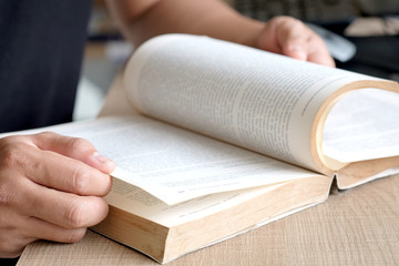 Hand young men holding open book and read books on the table in the university library