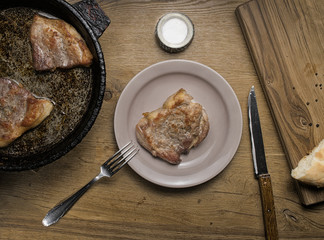 three fried pork steaks in a frying pan
