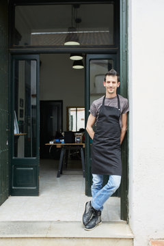 Portrait of a male artisan posing  in the front door of his atelier