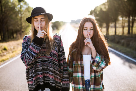Portrait of two teenager girls  make quiet sign
