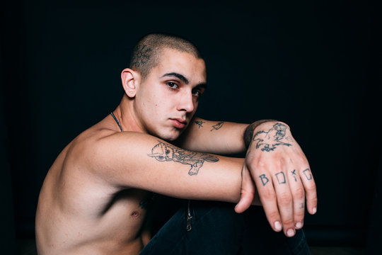 Tattooed young man portrait over black background