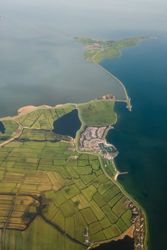 Aerial Shot of an island connected via a road which is also a dam that divides a lake from an ocean.