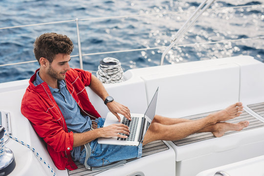 A Man Typing on Laptop on Sailboat