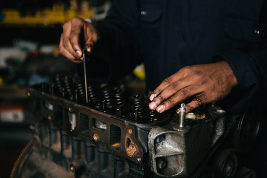 Mechanic fixing an engine for a head gasket repair in a garage.