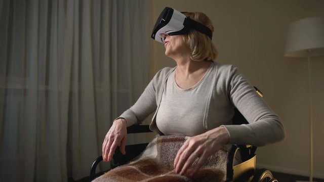 Woman in wheelchair wearing vr headset for the first time, happy and surprised