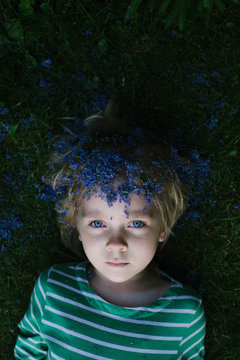 Little girl with Lilac petals on her head plays at dusk.