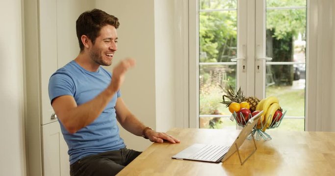 4K Attractive man relaxing at home, making a video call on computer. Slow motion.