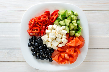 Fresh vegetables and cheese in a plate on a wooden table. Healthy food