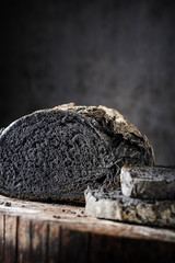 Fototapeta premium Sliced bread of black color on a wooden table