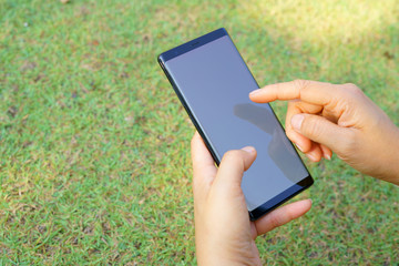 Female hand holding the smartphone Black and Green nature