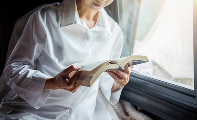 Reading a book. Beautiful female sitting on the bed and reading a book in her hands. Morning with a book in their hands.vintage color,selective focus