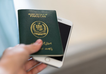 A hand holds Pakistan passport. Focus on the font on passport