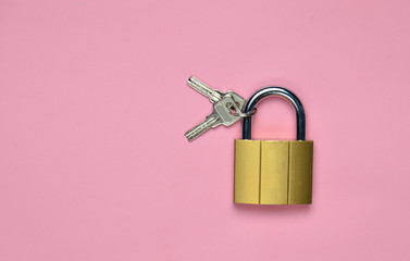 Golden closed lock with keys on a pink background. Copy space. Top View.