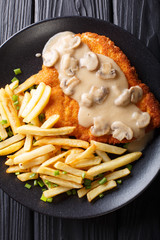 Jaeger Viennese schnitzel with French fries and mushrooms close-up. Vertical top view