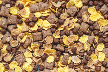 background of mixed breakfast cereal (chocolate balls, corn, grain, chocolate pads), top view