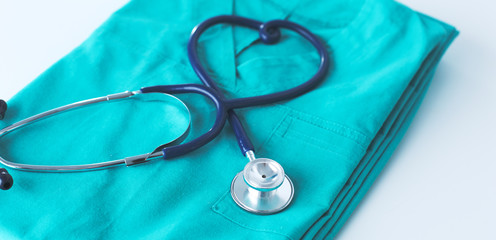 A stethoscope shaping a heart on a medical uniform, closeup