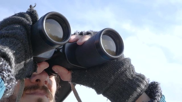 close up portrait of young bearded man in hat with binocular