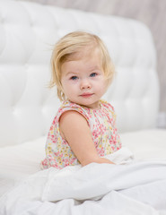 Smiling baby girl sitting on the bed