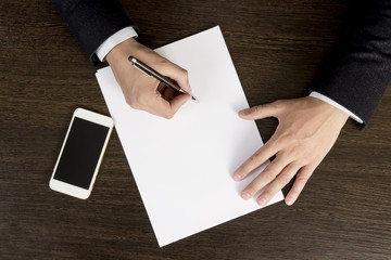 Obraz premium Hands of businessman on the desktop sign papers. The top view of the workflow in the office of the company. Sign the contract. Signing of a major transaction.