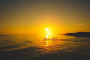 Naklejka na ściany i meble Silhouette of fishing boat and fisherman on sunset.