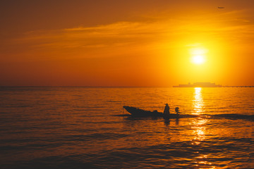 Silhouette of fishing boat and fisherman on sunset.