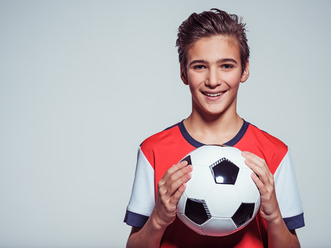 smiling teen boy in sportswear holding soccer ball