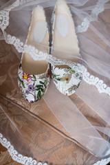 Shoes without heels with colorful flowers are covered with a veil. Wedding shoes 
