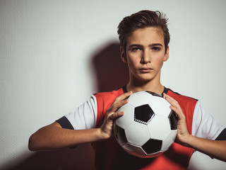 Photo of teen boy in sportswear holding soccer ball