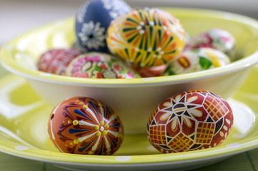 Group of wax painted Easter eggs in green spotted bowl