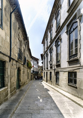 Fototapeta na wymiar Typical narrow alley paved with cobblestones and with old stone houses in the center of the old town of Guimaraes (Portugal)