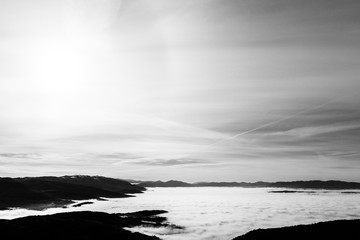 Fog filling Umbria valley, with layers of mountains and hills and sun filtered through the clouds