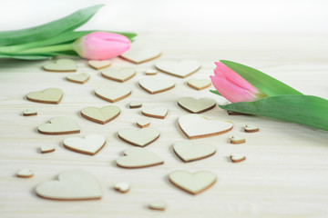 Couple of pink tulips on background of wooden hearts