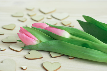 Romantic desktop with pink tulips on background of wooden hearts