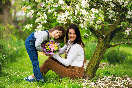 Young pregnant woman, receiving bouquet of colorful flowers from her child for Mothers Day