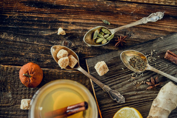 Vitamin tea with lemon and honey, ginger and spices on wooden background . The concept of spring beriberi and colds.