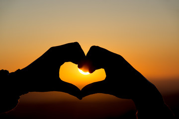 Fototapeta premium A heart hand gesture is silhouetted by the setting sun in Dartmoor, UK