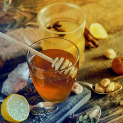 Vitamin healing tea with lemon and honey, ginger and spices on wooden background in rustic style. The concept of spring beriberi and colds. Square image.