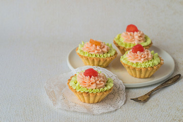 An appetizing dessert. Round cake with butter cream on a white dish on a light background.