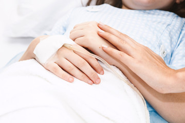 Fototapeta na wymiar Mother holding little girl hand with IV saline intravenous in hospital