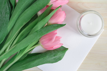 Pink tulips flat lay with white card and candle. Top view