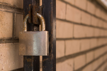 rusty closed padlock on the door with a yellow brick wall