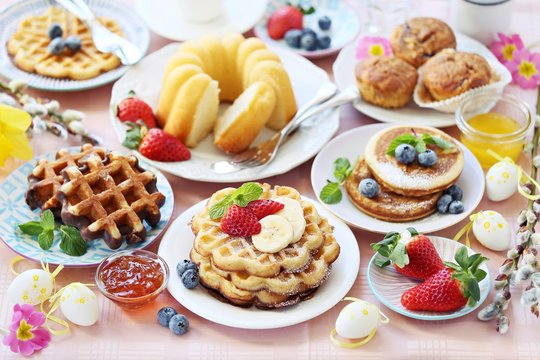 Easter dessert table. Pancakes,waffles and bundt cake with fresh berries and various of topping. Overhead view, copy space