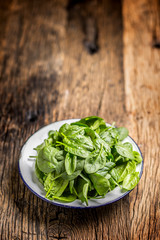 Spinach. Fresh baby spinach leaves in plate on woden table