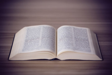 An opened holy bible on a wooden table
