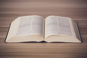 An opened holy bible on a wooden table