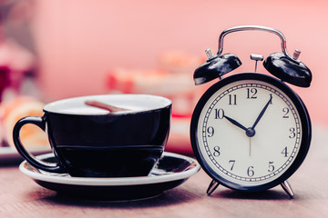 Black old clock with black coffee cup decoration on wooden table pink colortone