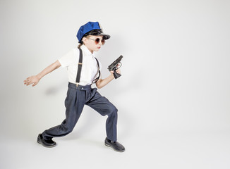 Little long-haired boy as a policeman runs, isolated on gray
