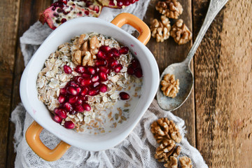 Breakfast: granola with pomegranate and walnuts on natural wooden background rustic. The concept of healthy and high-carbon nutrition.