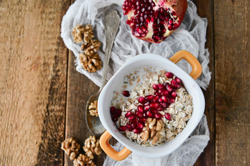 Breakfast: granola with pomegranate and walnuts on natural wooden background rustic. The concept of healthy and high-carbon nutrition.