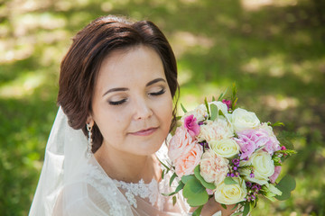 Fototapeta premium Beautiful newlyweds. Summer wedding. Bride with a bouquet of pink roses